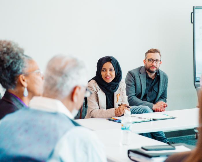 Ilhan Omar sits at a roundtable discussion next to her husband, Tim Mynett