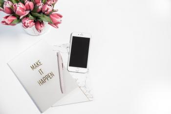 silver iphone next to a pen and a card 