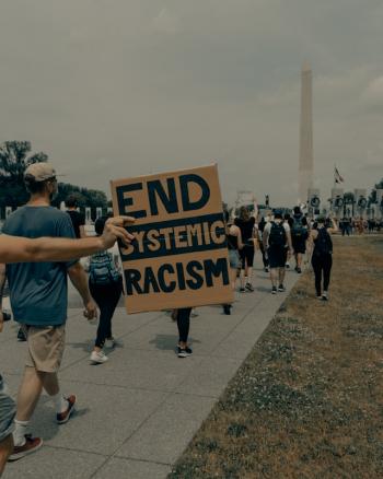 arm holding a sign reading stop systemic racism during a march