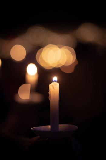 A lighted candle in a shallow dish