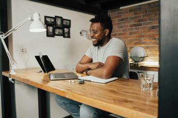 A black male student smiles as he looks at his laptop