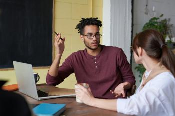 a black man gestures with his hand while talking to a white or Asian woman